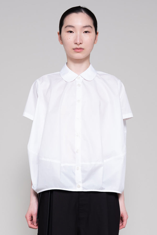 Person wearing a white shirt and black pants on a gray background