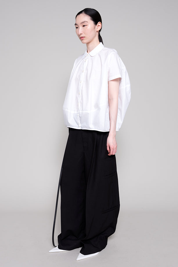 Person wearing a white shirt and black pants on a gray background