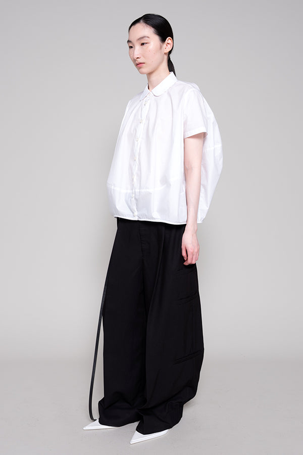 Person wearing a white shirt and black pants on a gray background