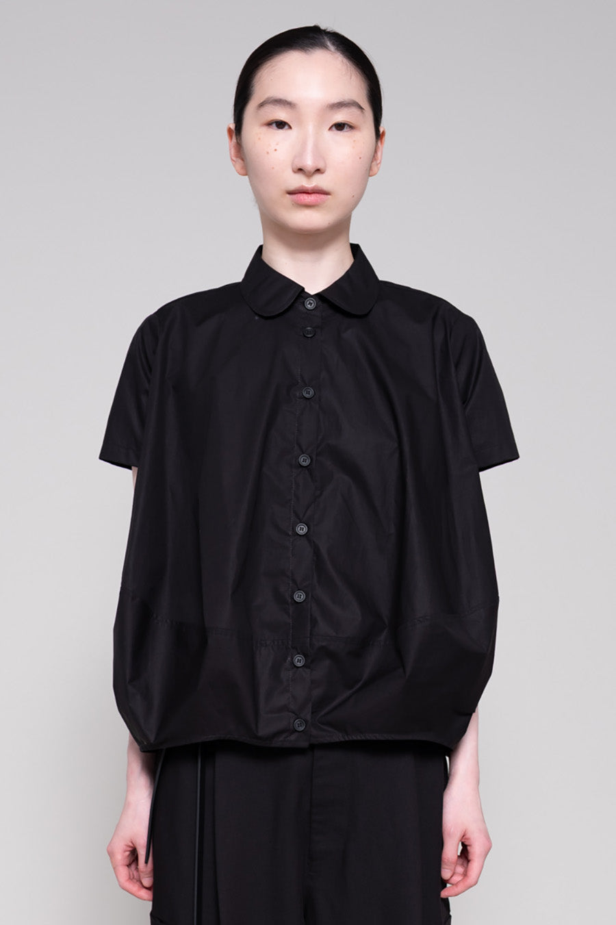 Person wearing a black shirt and pants on a plain background