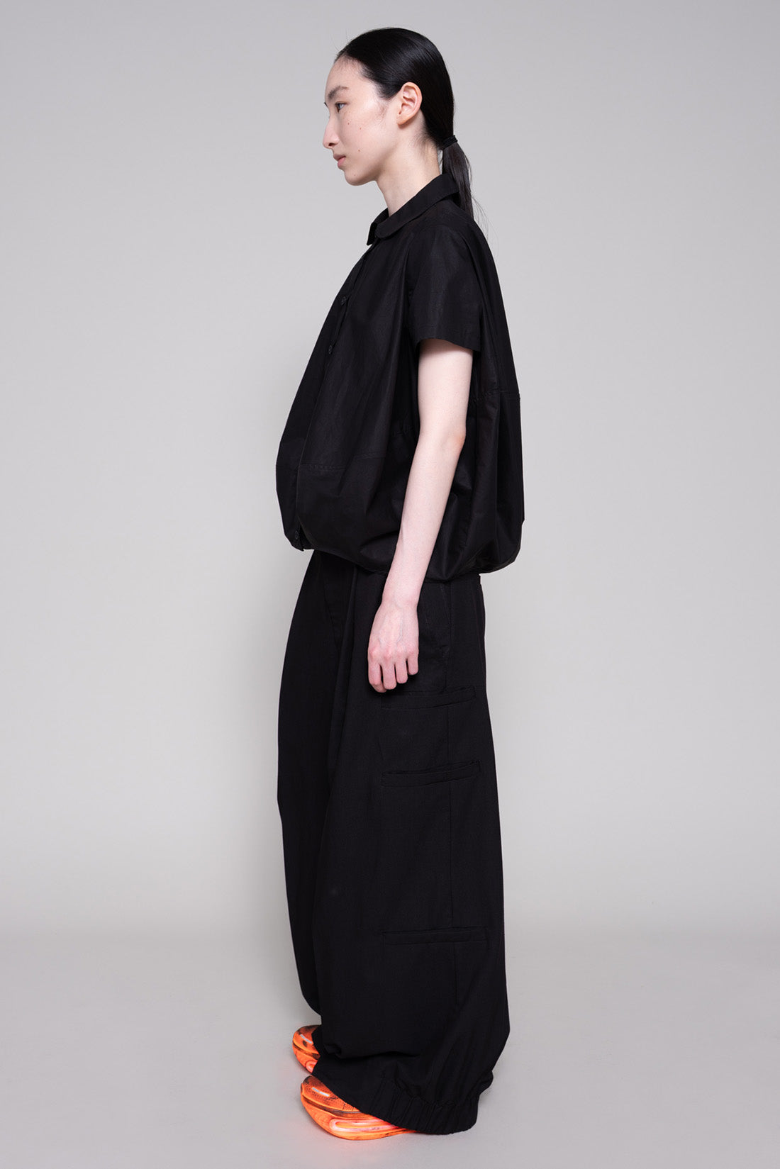 Person wearing a black shirt and pants against a plain background