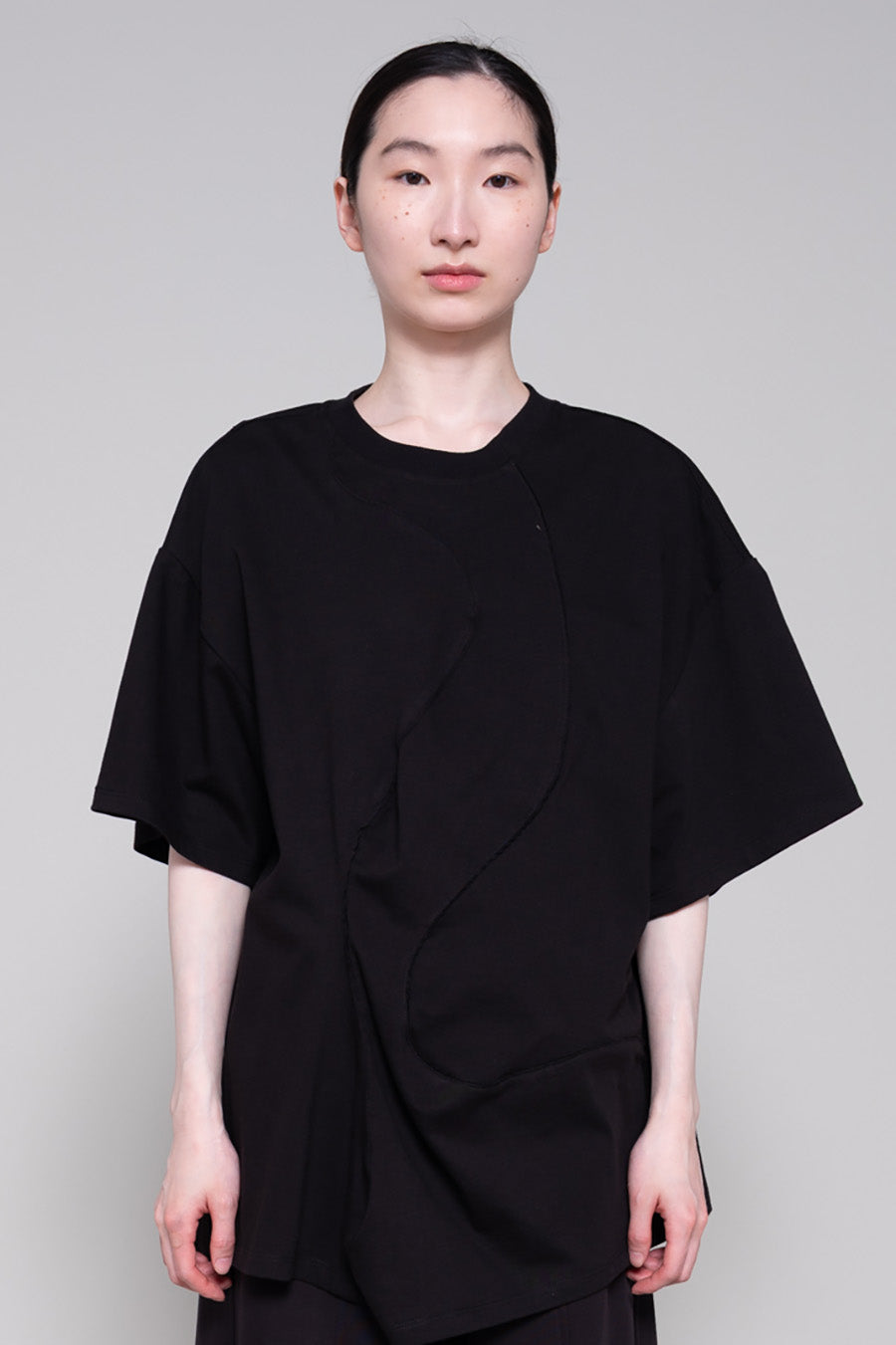 Person wearing a black tee and pants against plain background