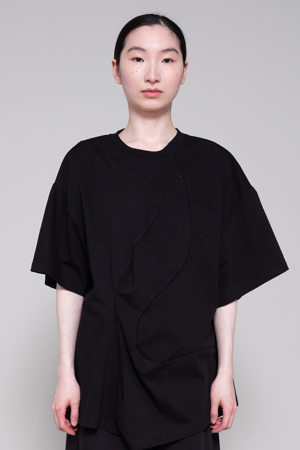 Person wearing a black tee and pants against plain background