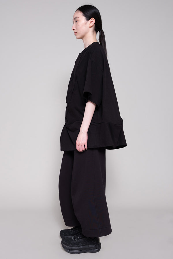 Person wearing a black tee and pants against plain background