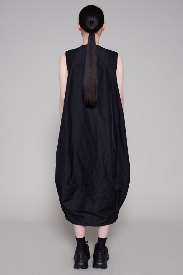 Person wearing a black sleeveless dress against a plain background