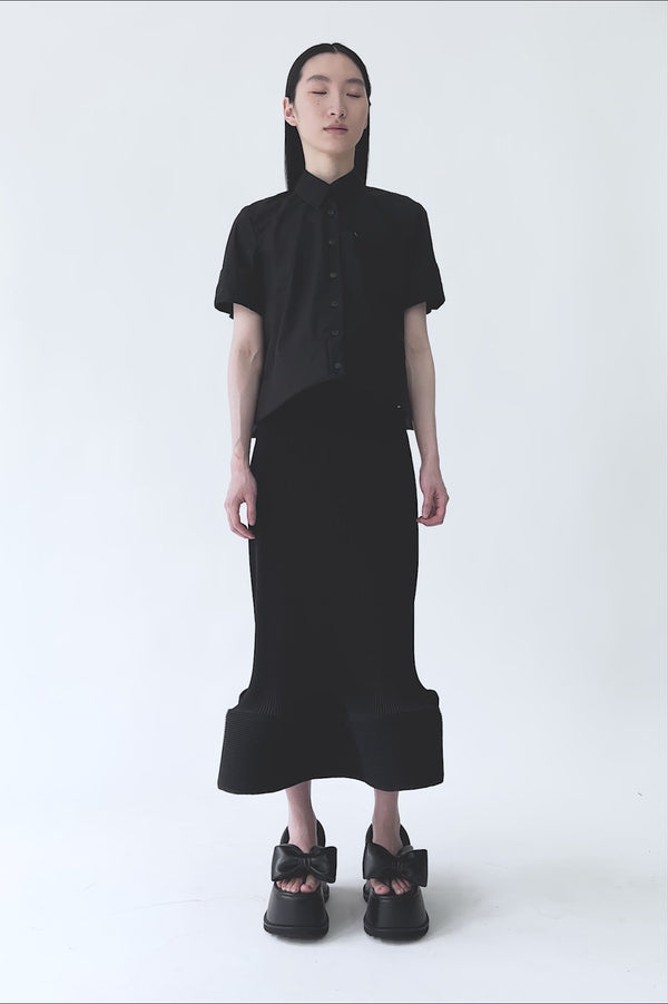 MELITTA-BAUMEISTER-Ripple-Wavy-Skirt-Black-VIDEO-OF-MODEL-RECEIVING-POINTY-SHOULDER-BAG-TURNING-THEN-LEAVING-FRAME-COMES-BACK-AND-PUTS-BAG-ON-FLOOR