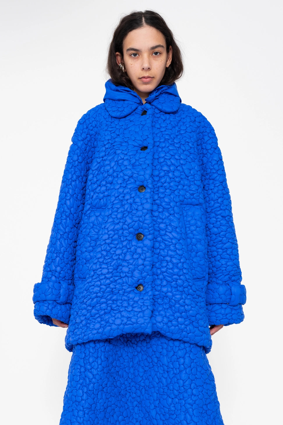 female-wearing-electric-blue-quilted-windbreaker-with-flower-embroidery-on-white-background-close-up-front