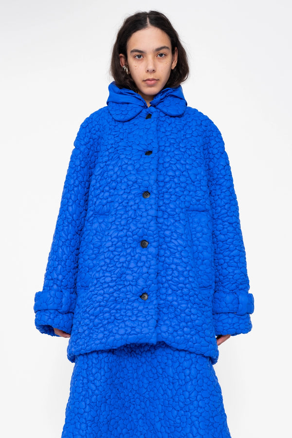 female-wearing-electric-blue-quilted-windbreaker-with-flower-embroidery-on-white-background-close-up-front