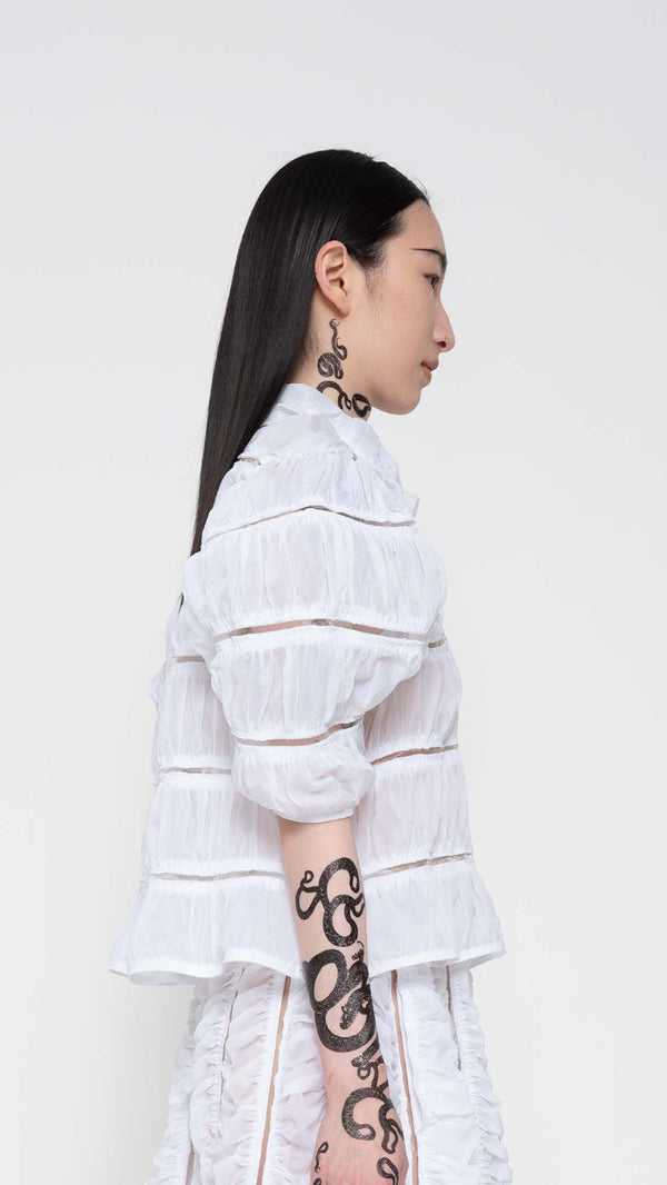 SIDE-VIEW-OF-BRUNETTE-WEARING-WHITE-RUCHED-CARDIGAN-HOLDING-BAG-ZOOM-ABOVE-WAIST