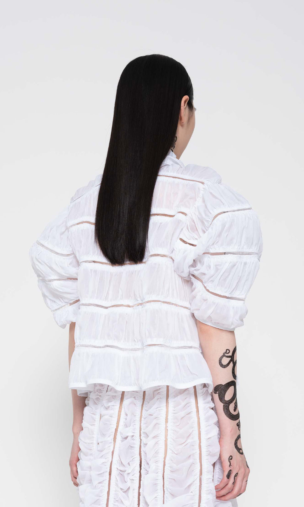 back-VIEW-OF-BRUNETTE-WEARING-WHITE-RUCHED-CARDIGAN-HOLDING-BAG-ZOOM-ABOVE-WAIST